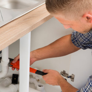 plumber working on a sink pipe