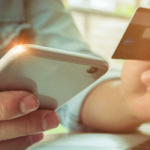 man holding cell phone and debit card